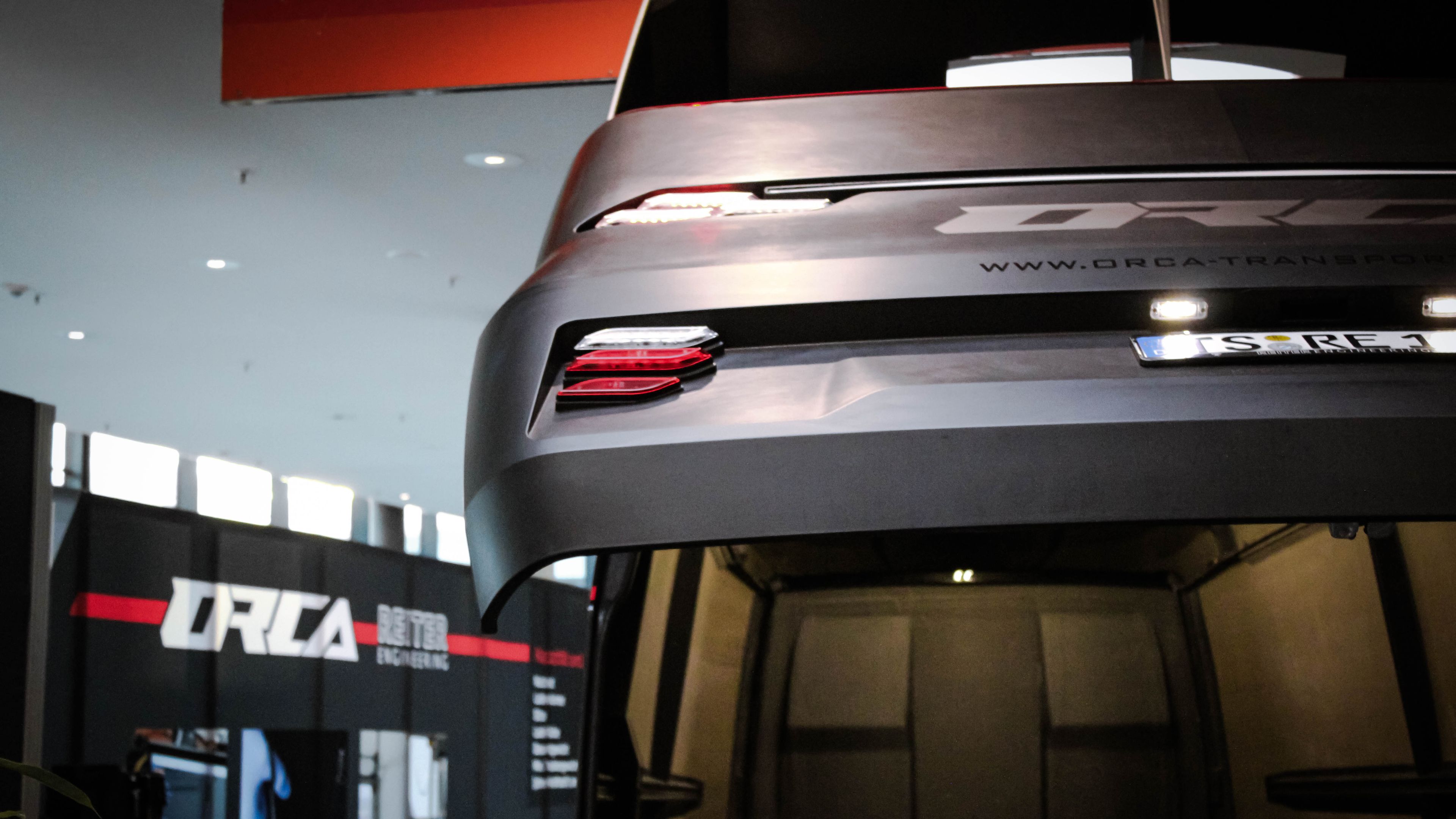 Nahaufnahme der markanten Heckleuchten und der aerodynamischen Form des ORCA Transporters bei geöffneter Klappe.