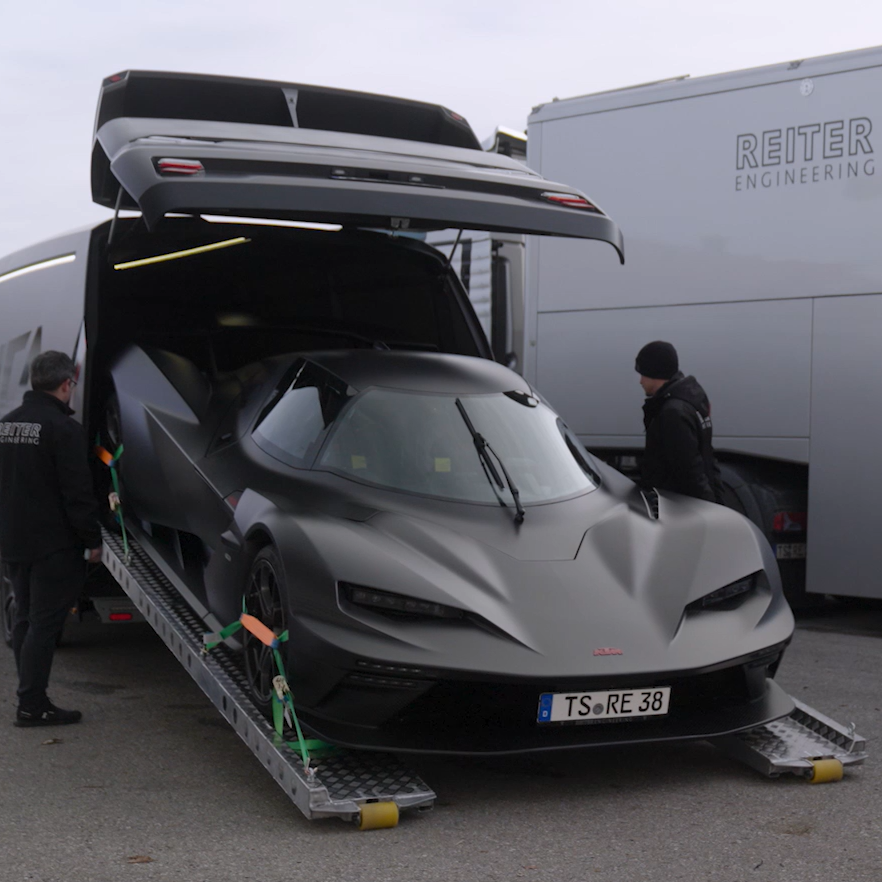 Ein schwarzer Rennwagen wird über Rampen in das Heck eines ORCA Transporters der Reiter Engineering Rennteam-Abteilung verladen
